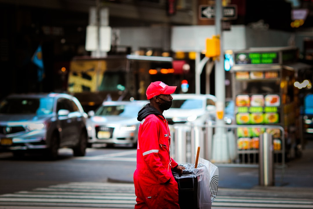woman in red jacket and red hat walking on pedestrian lane during daytime