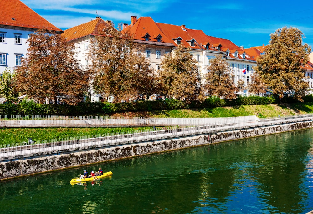 Gelbes Kajak auf dem Fluss in der Nähe des braunen Betongebäudes tagsüber