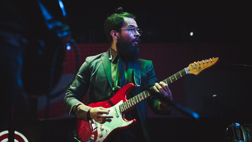 man in green jacket playing electric guitar