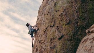 man in black t-shirt climbing on brown rock during daytime