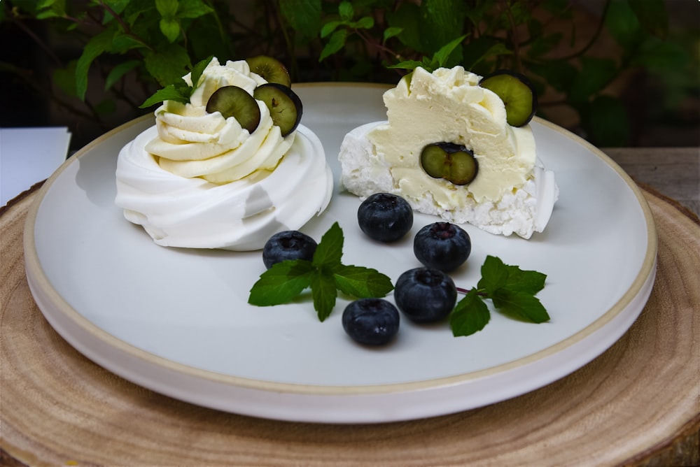 Torta ricoperta di glassa bianca con bacche nere su piatto di ceramica bianca