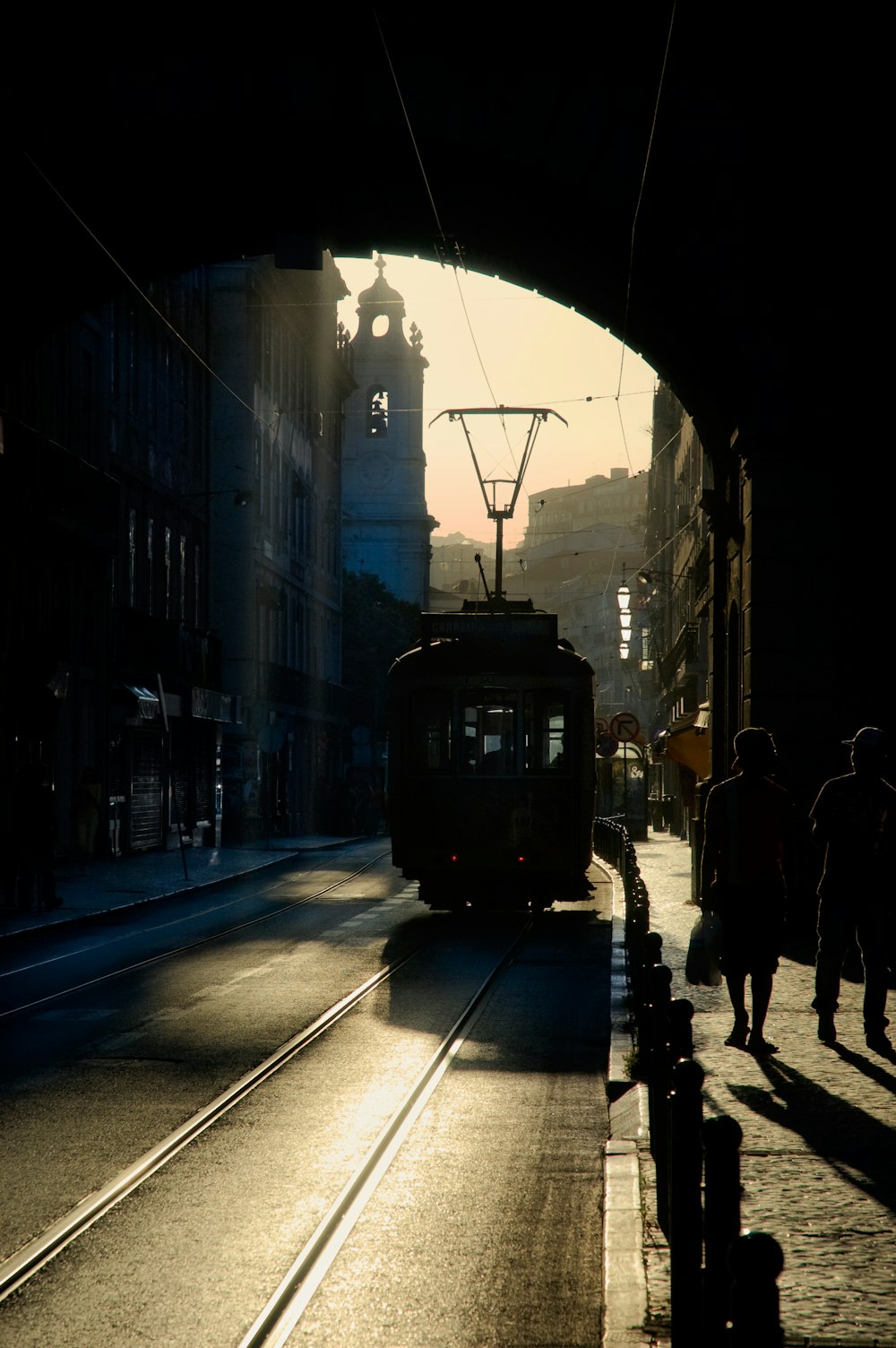 people walking on sidewalk near black tram during night time