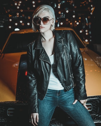 woman in black leather jacket and blue denim jeans wearing black sunglasses