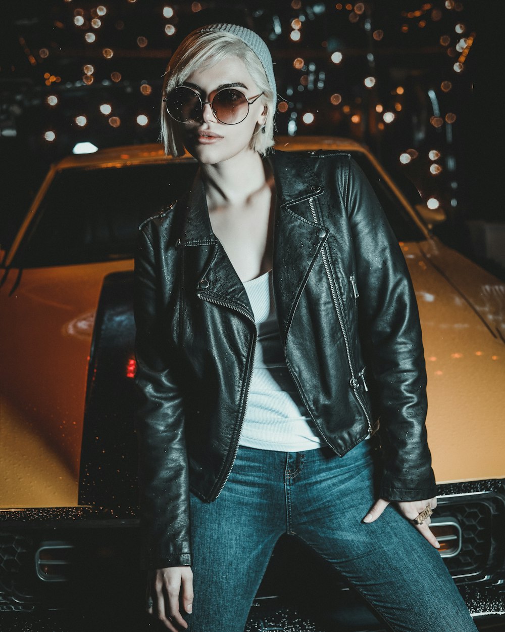 woman in black leather jacket and blue denim jeans wearing black sunglasses