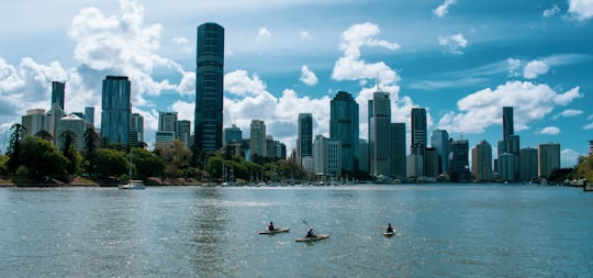 people riding on boat on water near city buildings during daytime in Brisbane QLD Australia
