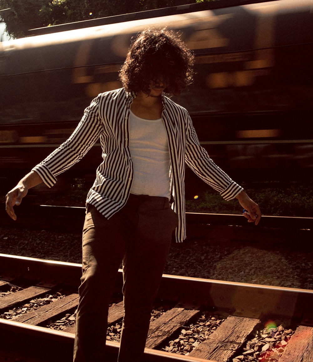 man in black and white striped long sleeve shirt standing on train station