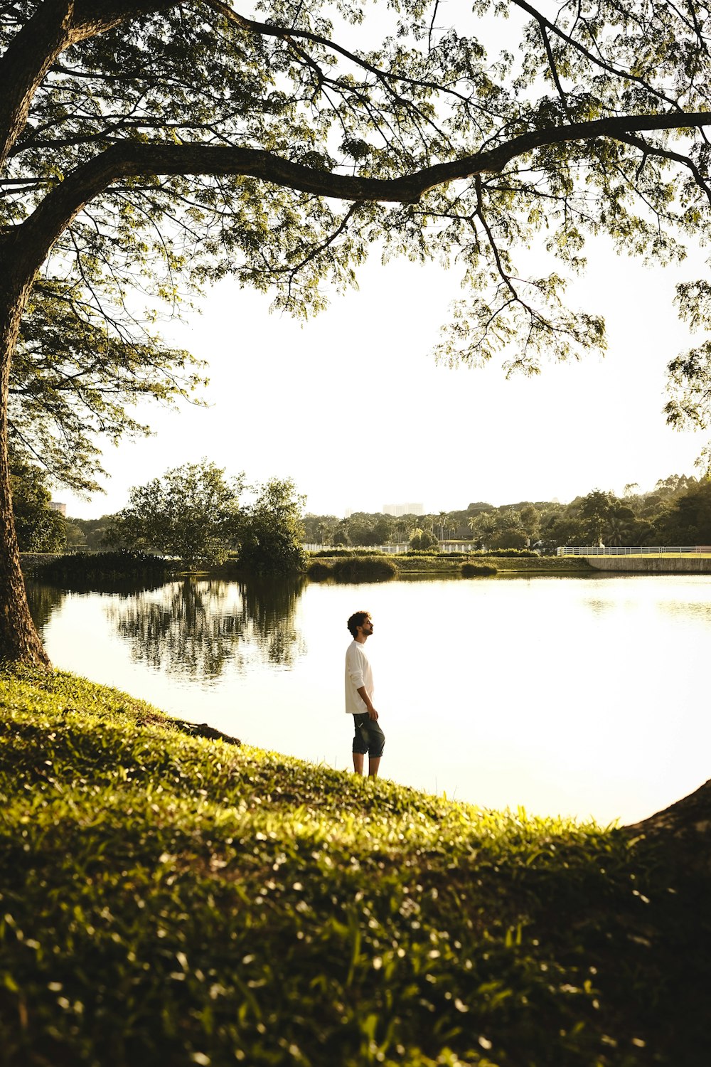 man in white shirt standing near lake during daytime