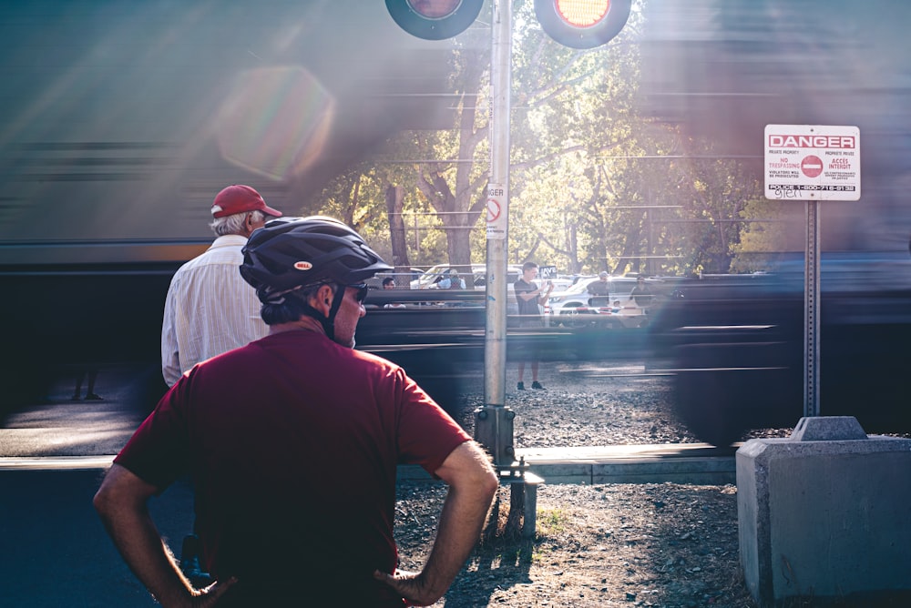 man in black crew neck t-shirt wearing black helmet standing near train rail during daytime