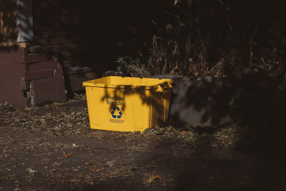 yellow garbage bin beside green plant