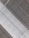 A ceiling with a prominent central duct running through it. The duct has a curved, grid-like pattern and is painted white. Surrounding the duct are gray metallic panels arranged in a linear fashion. The structure appears industrial with visible beams and metallic elements.