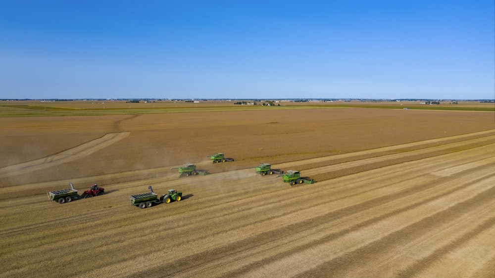 tractor verde y negro en el campo marrón bajo el cielo azul durante el día