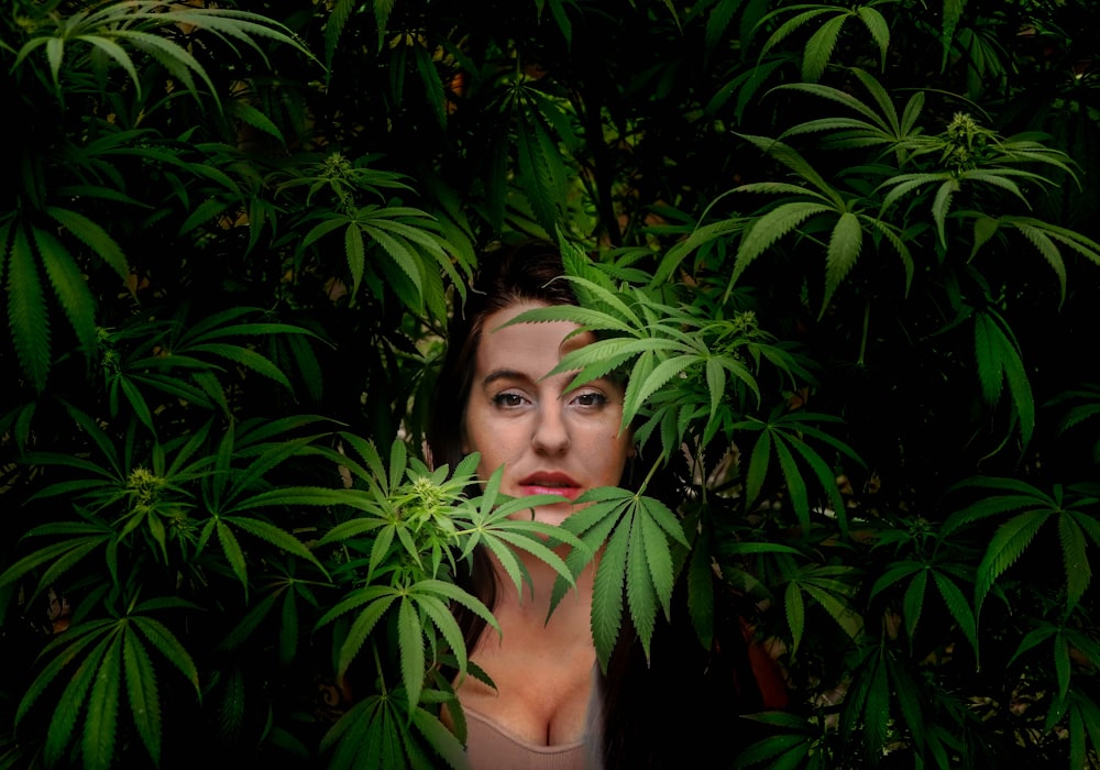 woman in black tank top standing beside green plant