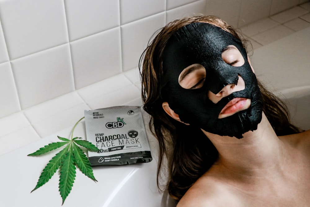 woman in bathtub with black face mask
