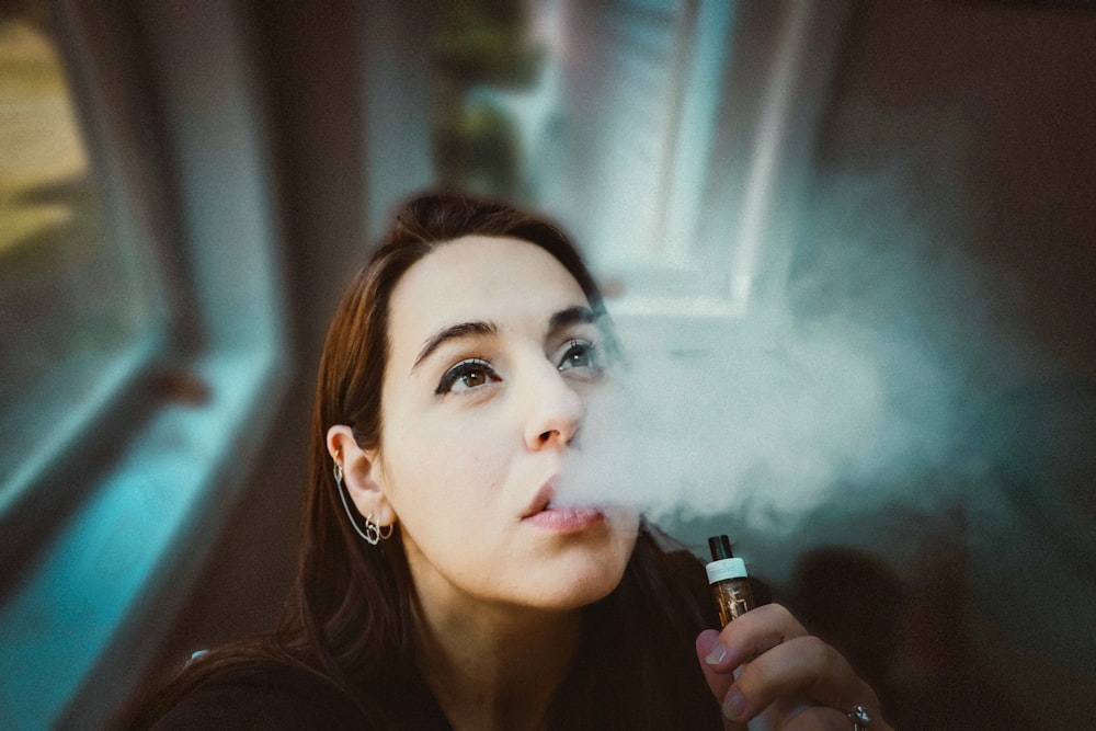 Mujer sosteniendo tubo negro y dorado tipo vape