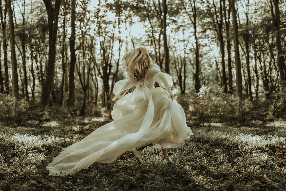 woman in white dress standing on brown dried leaves during daytime