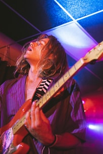 Close-up of a guitarist passionately playing blues riffs under colorful festival lights.