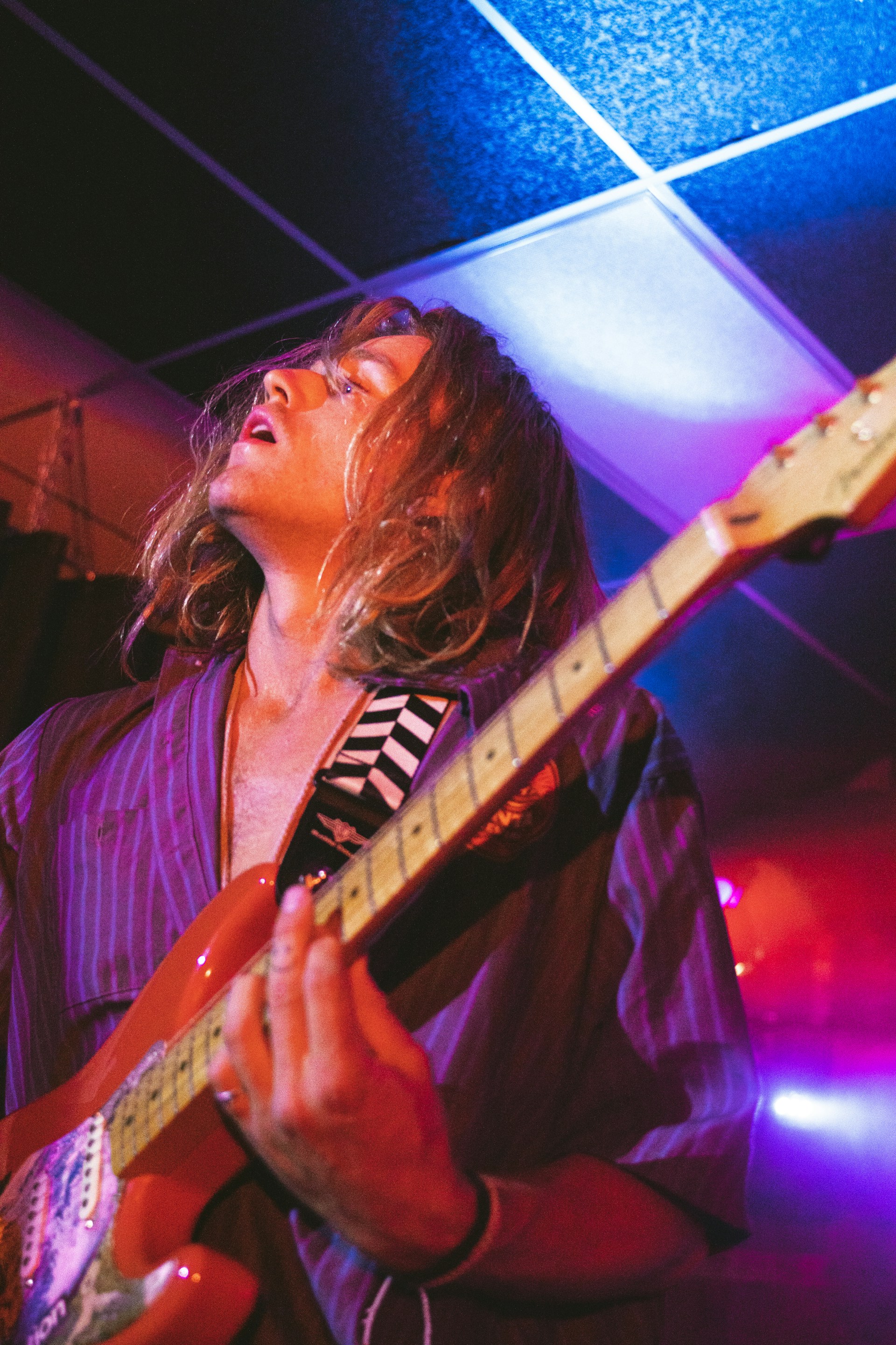 Johnny Cordon passionately playing his signature pink guitar under vibrant stage lights, capturing the energy of a 50s rock and roll show.
