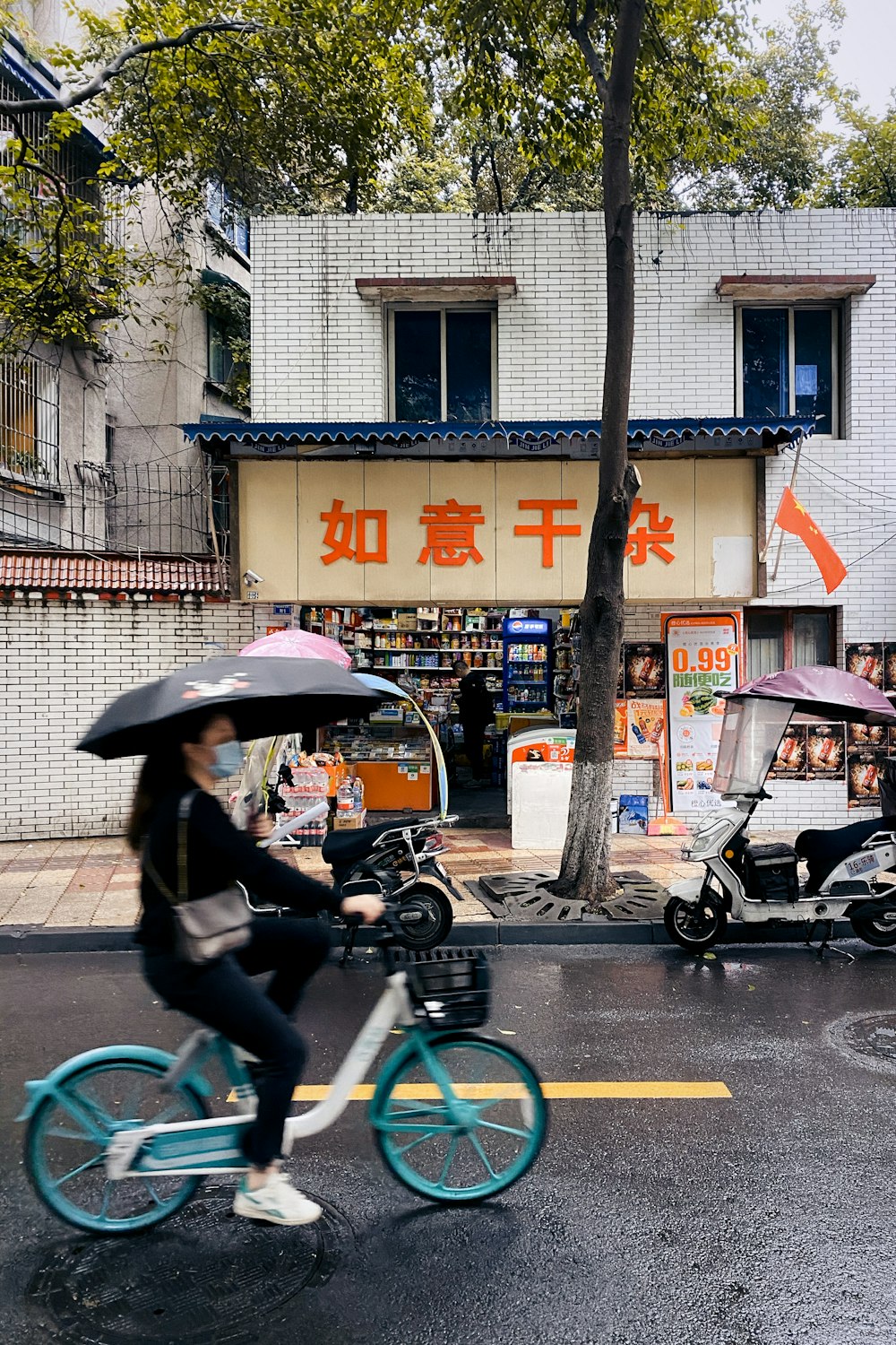 woman in black jacket and black pants riding bicycle with umbrella on road during daytime