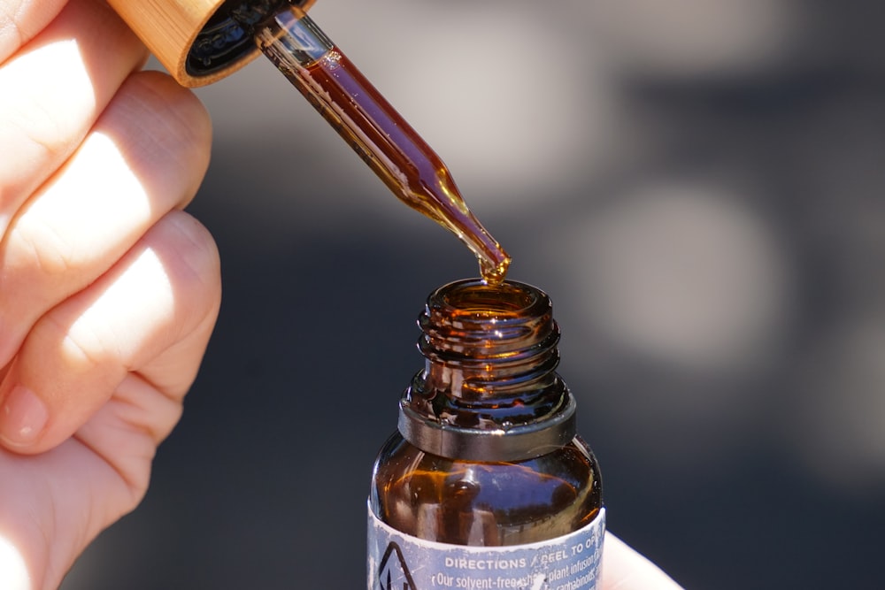 person holding brown glass bottle