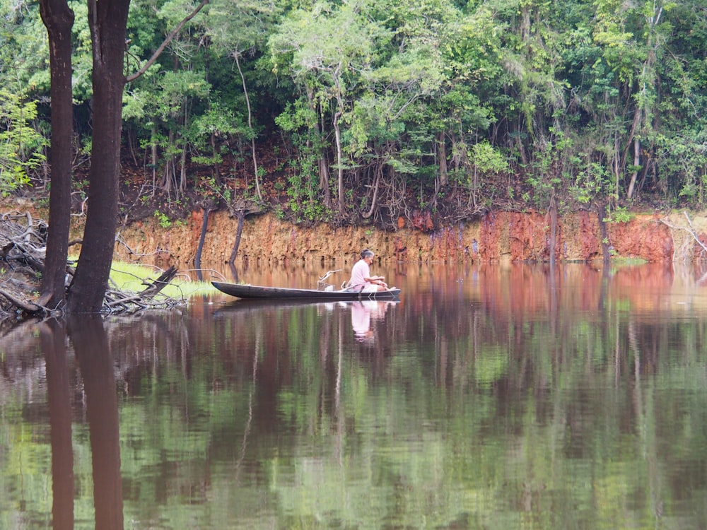 man in brown boat on lake during daytime