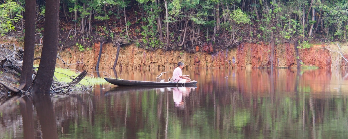 man in brown boat on lake during daytime