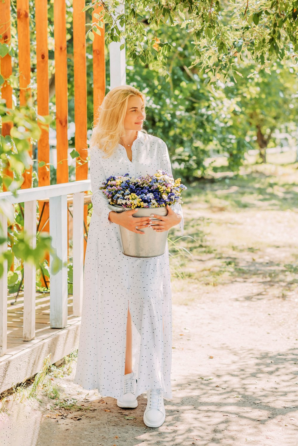 woman in white and blue floral dress holding bouquet of flowers