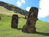 brown rock formation on green grass field during daytime