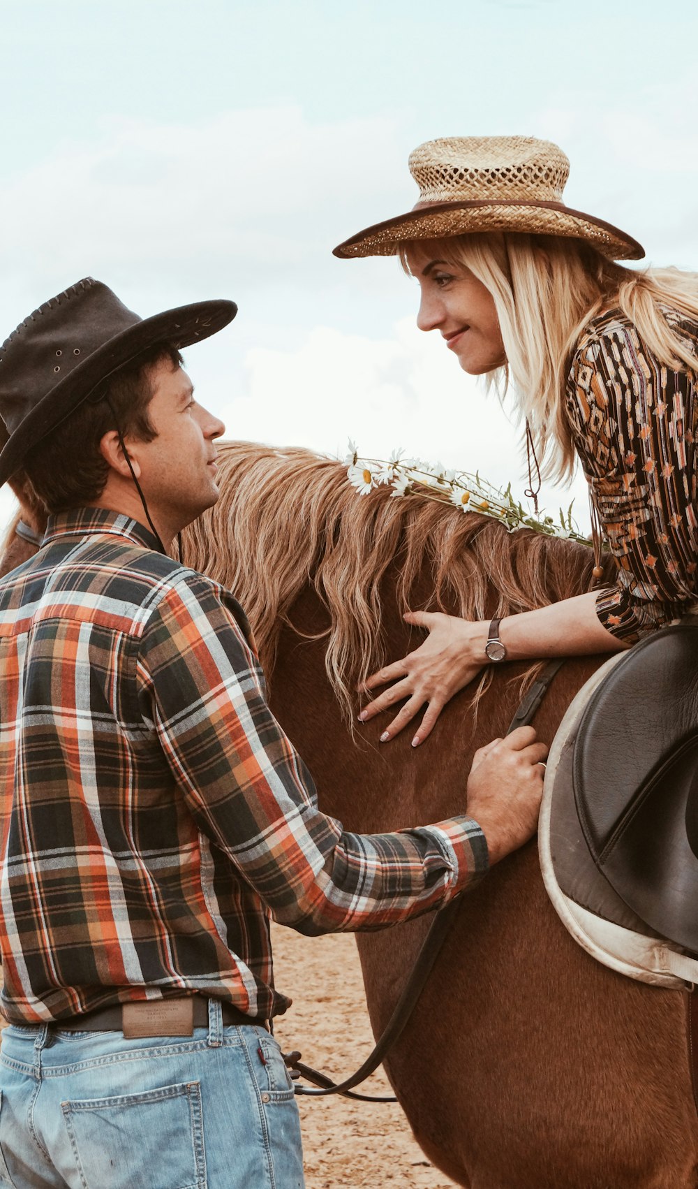 man in blue white and red plaid dress shirt and woman in brown cowboy hat