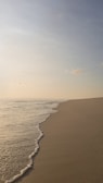 Golden sands and turquoise waves at a peaceful beach in Goa during sunrise.