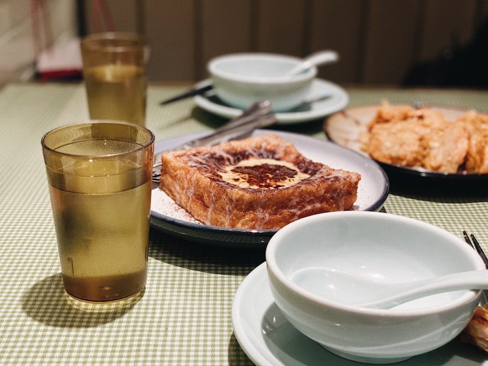 clear drinking glass beside white ceramic plate with food