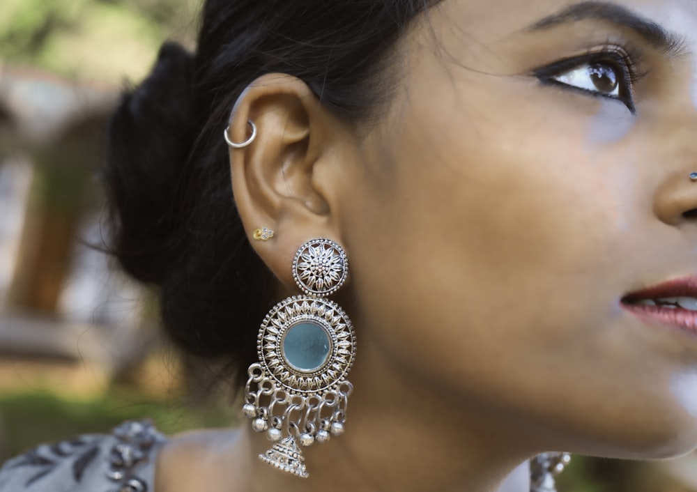 woman wearing silver and blue gemstone stud earring
