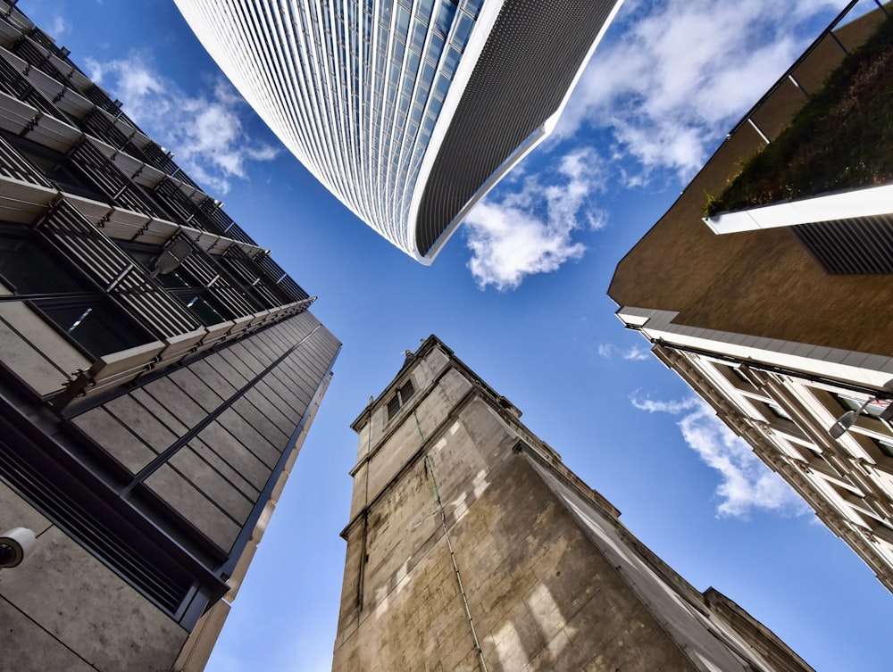 worms eye view of brown concrete building under blue and white sunny cloudy sky during