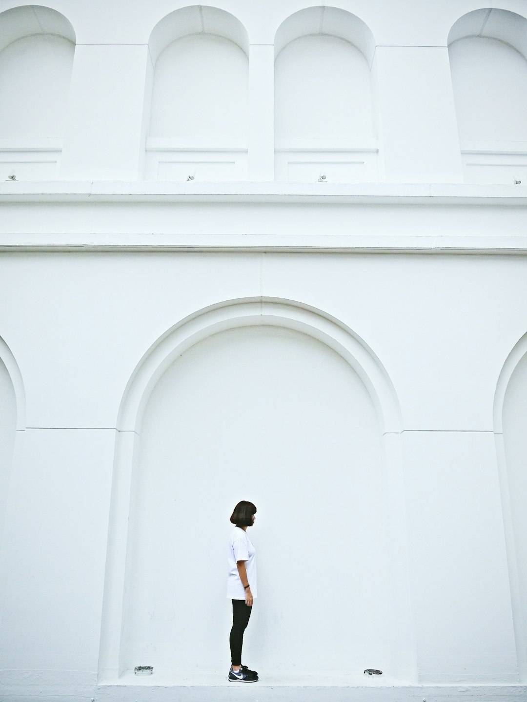 woman in white dress standing in front of white concrete building during daytime