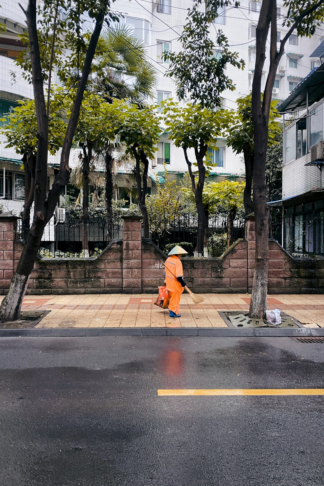 man in orange hoodie walking on sidewalk during daytime