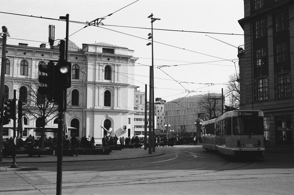 grayscale photo of tram on road near building