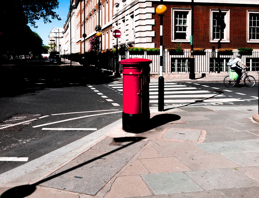 red mail box on sidewalk during daytime