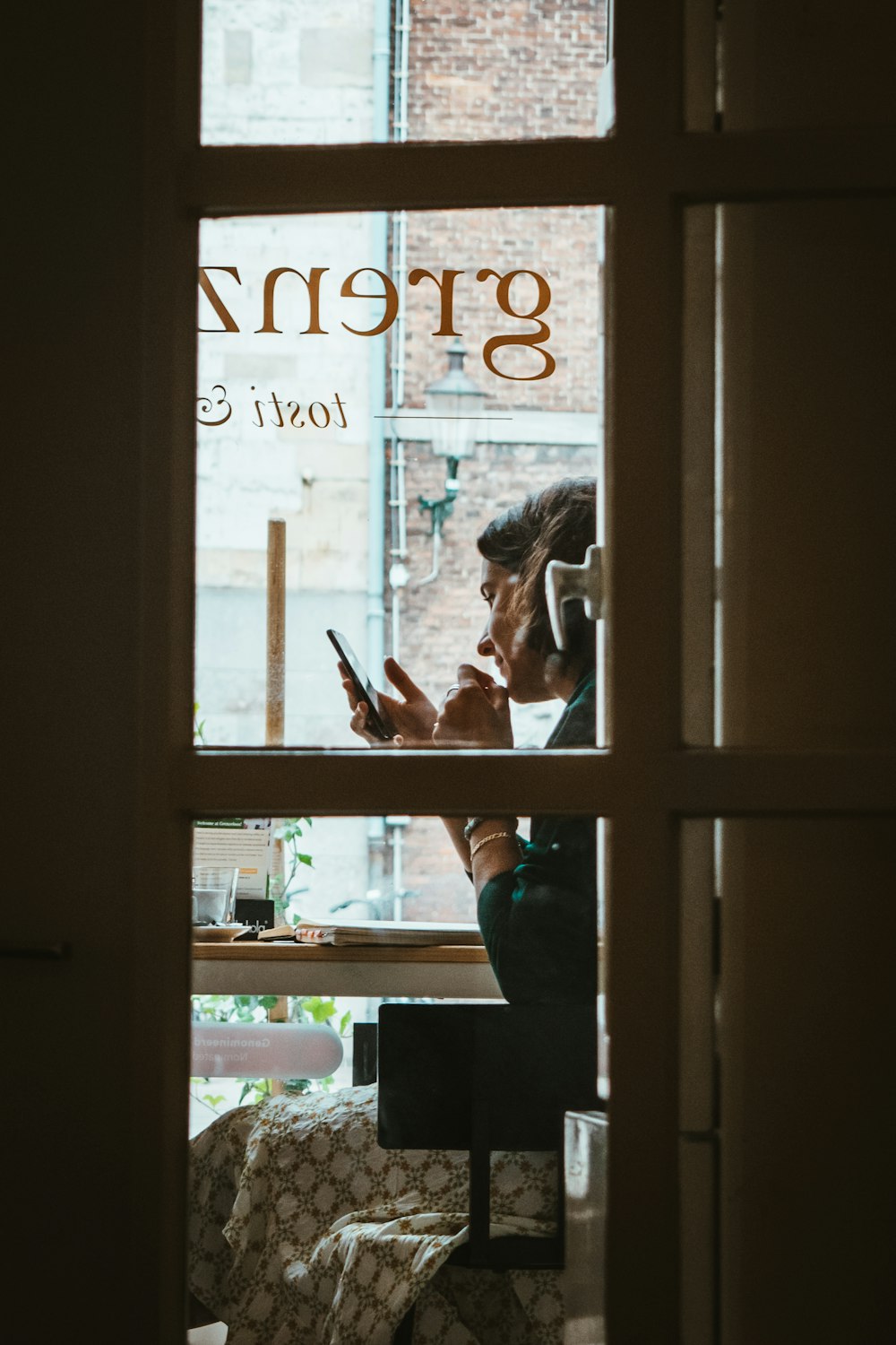 woman in blue long sleeve shirt standing beside glass window