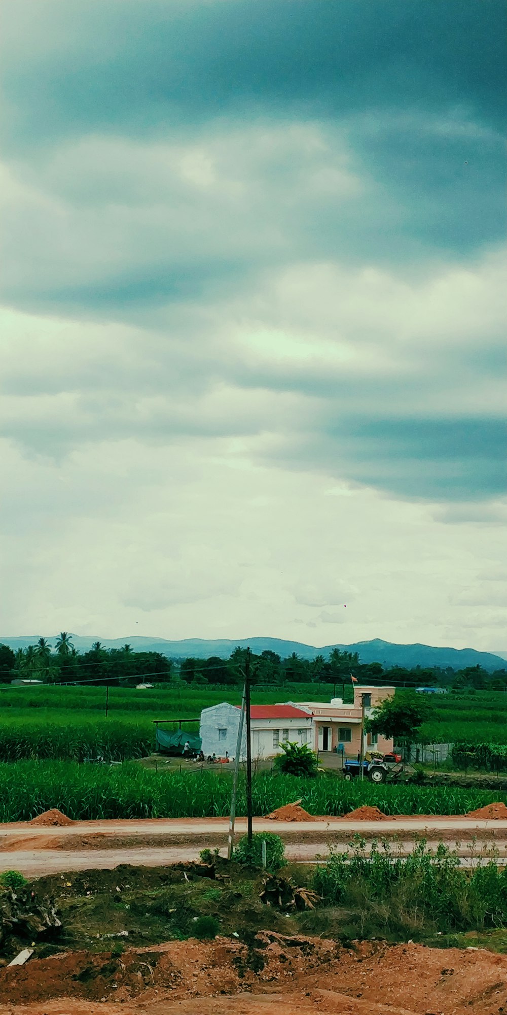 green grass field near houses under cloudy sky during daytime