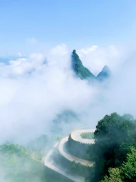 A serene mountain road winding through misty hills under a clear sky.
