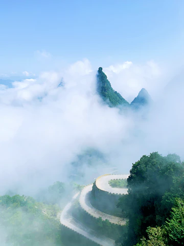 A serene mountain road winding through misty hills under a clear sky.