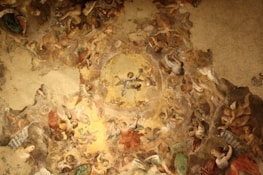 A richly detailed ceiling fresco filled with numerous angels and figures, depicted in dynamic poses and positioned around a central heavenly figure. The artwork features intricate patterns and a harmonious blend of colors, showcasing a sense of movement and divine presence.