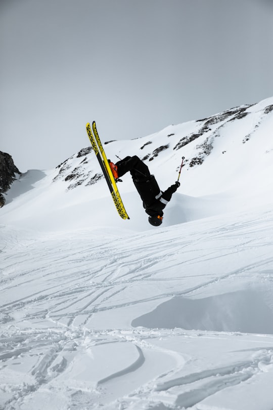 man in black jacket and black pants riding yellow snowboard on snow covered mountain during daytime in Grimentz Switzerland