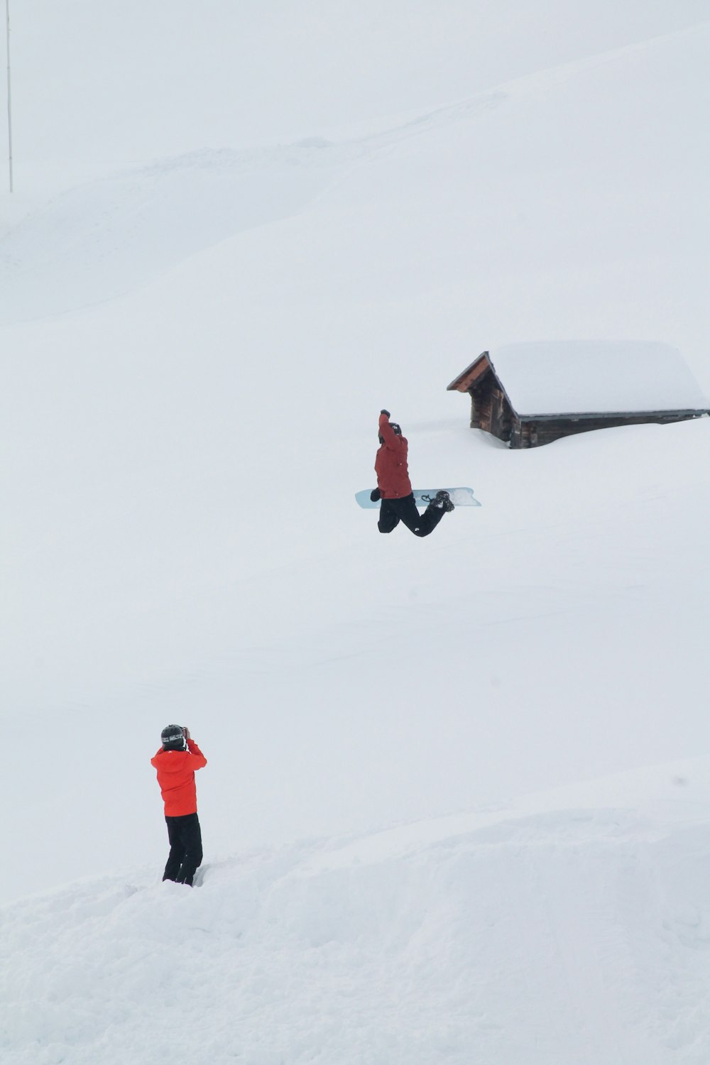 Person in roter Jacke und schwarzer Hose, die tagsüber auf schneebedecktem Boden geht