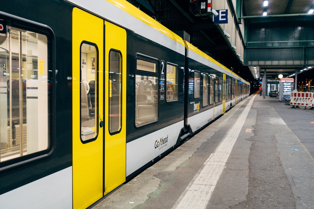 gelb-weißer Zug tagsüber auf dem Bahnhof