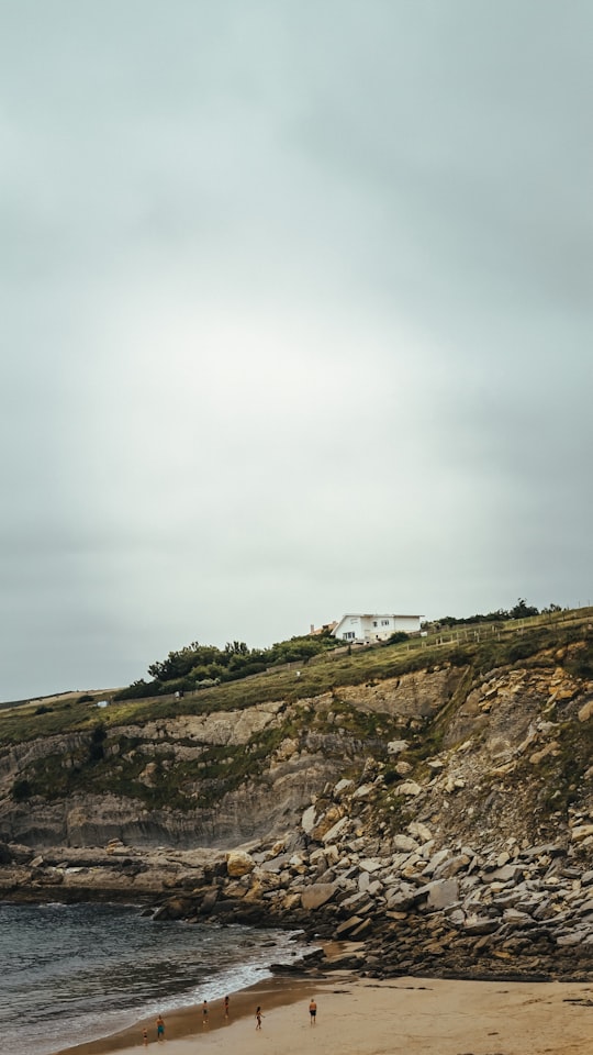 white house on brown and green hill under white clouds in Cantabria Spain