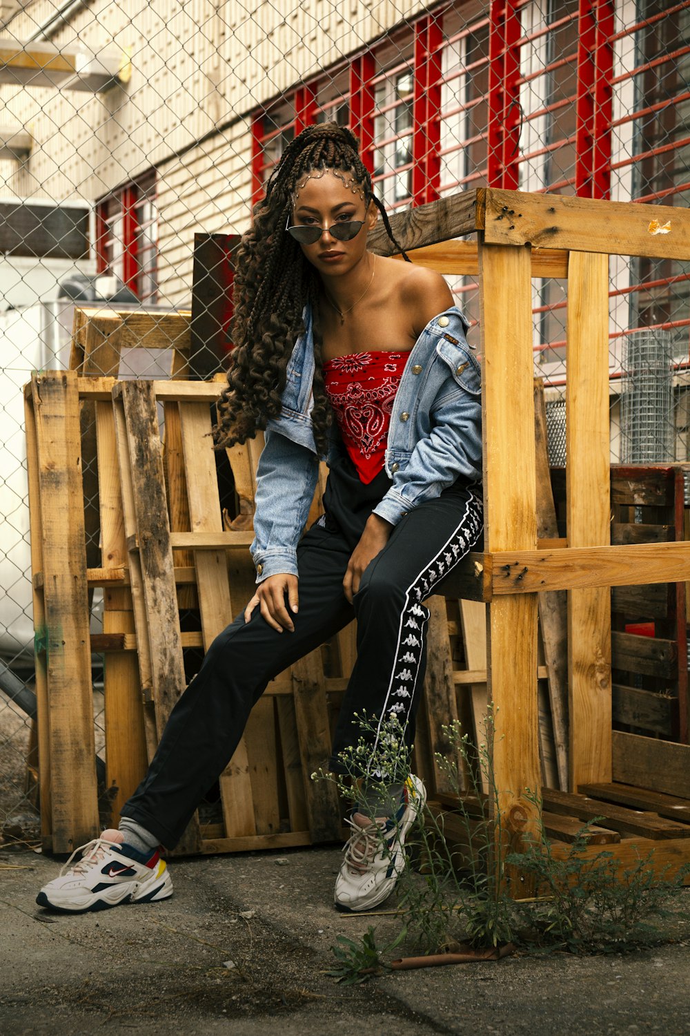 woman in gray tank top and black pants sitting on brown wooden fence