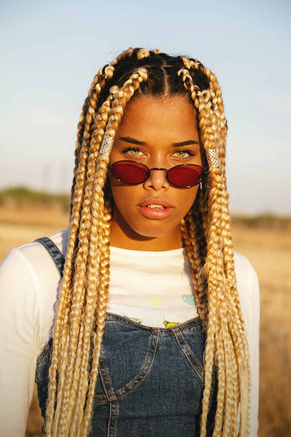 Frau in weißem Hemd und blauer Jeans mit brauner Sonnenbrille