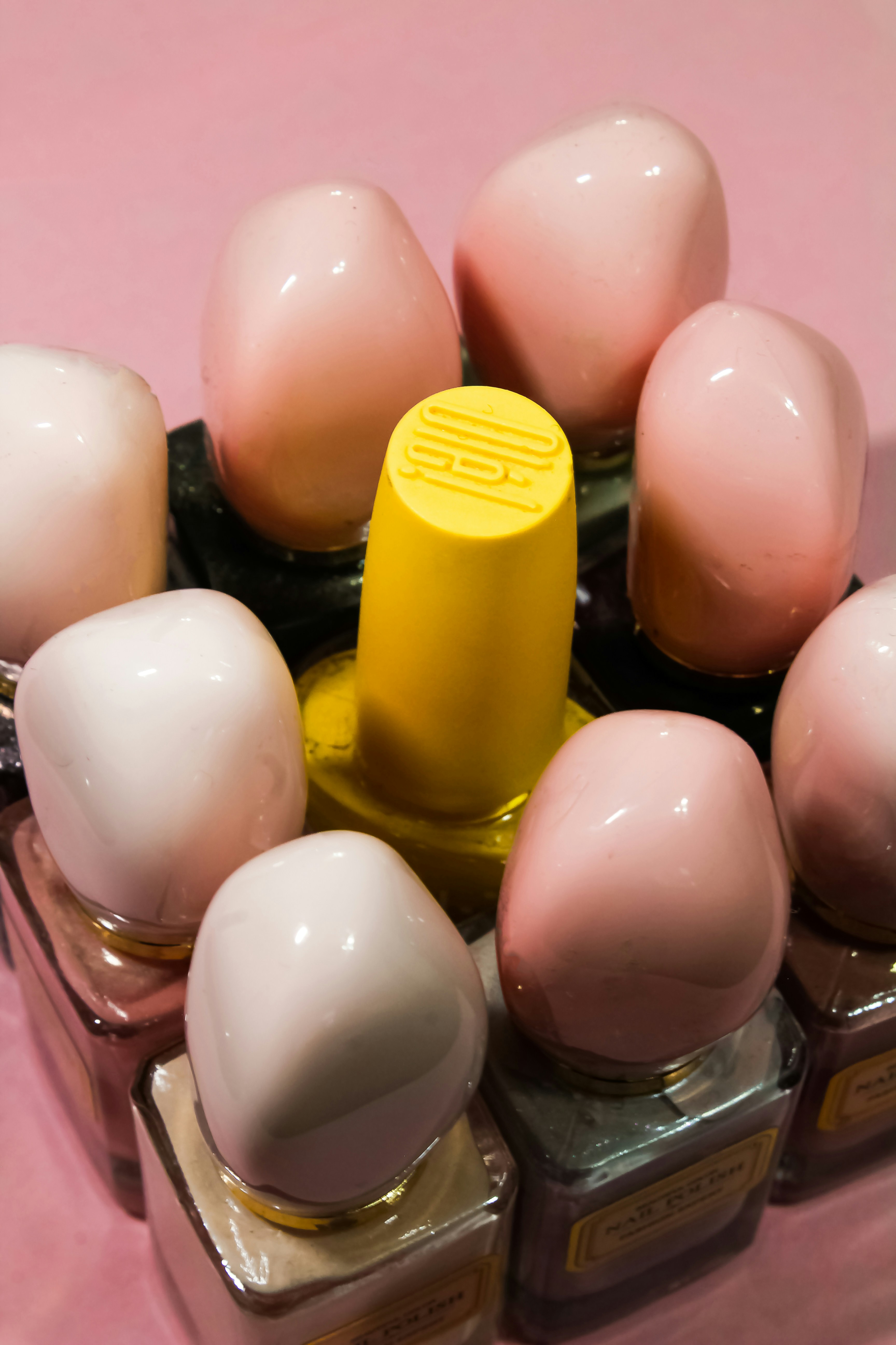 Nail polish bottles in pink and red shades arranged neatly on white background