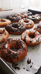 A cheerful baker frosting a tray of freshly made vegan donuts in a cozy kitchen.