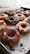 A colorful assortment of freshly made donuts with powdered sugar and glaze on a bakery tray.